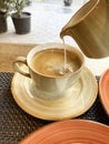 Cream being poured into a cup of coffee from a milk jug