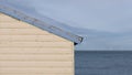 Cream and blue beach hut with peeling paint and wind farm in distance Royalty Free Stock Photo