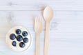 White bowl of Greek yogurt and fresh berries on a light wooden background, top view. Dessert