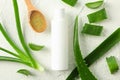 Cream bottle with space for text, wooden spoon, aloe vera slices and leaves on white table, top view Royalty Free Stock Photo