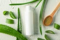 Cream bottle with space for text, wooden spoon, aloe vera slices and leaves on white table, top view Royalty Free Stock Photo