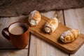 Cream cakes on a wooden plate with a cup of coffee with milk. The concept of natural and delicious food. Royalty Free Stock Photo