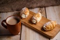 Cream cakes on a wooden plate with a cup of coffee with milk. The concept of natural and delicious food. Royalty Free Stock Photo