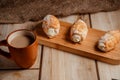 Cream cakes on a wooden plate with a cup of coffee with milk. The concept of natural and delicious food. Royalty Free Stock Photo