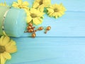 Cream capsule yellow flowers on chamomile blue wooden protection