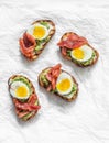 Cream cheese, avocado, red salted fish, boiled egg sandwiches on a light background, top view