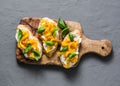 Cream cheese, roasted yellow bell pepper, basil bruschetta on cutting board on grey background Royalty Free Stock Photo