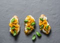 Cream cheese, roasted yellow bell pepper, basil bruschetta on on grey background, top view. Copy space Royalty Free Stock Photo