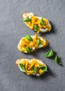 Cream cheese, roasted yellow bell pepper, basil bruschetta on on grey background, top view. Copy space Royalty Free Stock Photo