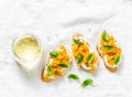 Cream cheese, roasted yellow bell pepper, basil bruschetta and white wine on light background, top view. Flat lay Royalty Free Stock Photo