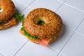 Cream cheese and smoked salmon bagel, on white ceramic squared tile table background, with copy space for text Royalty Free Stock Photo