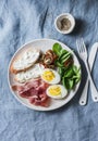 Cream cheese toast, boiled egg, prosciutto, spinach, tomatoes - delicious healthy breakfast or snack on blue background Royalty Free Stock Photo