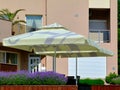 cream color canvas awning and parasol in bright sun light with patio garden