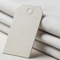 Cream-colored tag with a grommet hole rests against folded textured beige fabric. The tag has a Royalty Free Stock Photo