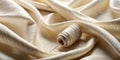 Cream-colored textile draped elegantly with a spool of thread and needle, showcasing its luxurious texture and subtle sheen. Royalty Free Stock Photo