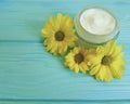 Cream cosmetic container product handmade glass ointment yellow flowers on blue wooden background Royalty Free Stock Photo