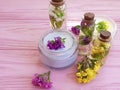 Cream cosmetic, fresh essence flowers on a pink wooden background, organic alternative