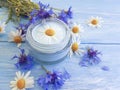 Cream cosmetic flowers cornflower, handmade treatment product camomile on a wooden background