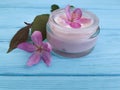 Cream cosmetic lotion freshness glass essence magnolia handmade pink flowers on blue wooden Royalty Free Stock Photo