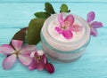 Cream cosmetic lotion moisturizer protection glass essence magnolia handmade pink flowers on blue wooden Royalty Free Stock Photo