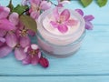 Cream cosmetic lotion ointment relaxation moisturizer protection glass essence magnolia handmade pink flowers on blue wooden Royalty Free Stock Photo