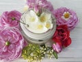 Cream organiccosmetic rose, jasmine plant on a white wooden background
