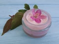 Cream cosmetic lotion protection glass essence magnolia handmade pink flowers on blue wooden Royalty Free Stock Photo