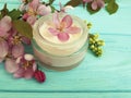 Cream cosmetic pink flowers on mint wood scrub, handmade