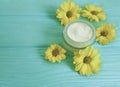 Cream cosmetic container product glass ointment yellow flowers on blue wooden background Royalty Free Stock Photo