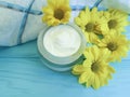 Cream cosmetic container product ointment yellow flowers on blue wooden background Royalty Free Stock Photo