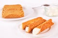 Cream filled brandy snaps served on a plate. Unfilled snaps and a pot with cream in the background Royalty Free Stock Photo