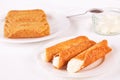 Cream filled brandy snaps served on a plate. Unfilled snaps and a pot with cream in the background