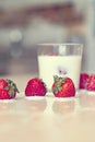 Cream in a glass. Cream splashed out of the glass, on the table, when strawberries were added to the glass.
