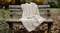 Cream Knit Blanket on Rustic Wooden Bench in Autumn Park Royalty Free Stock Photo