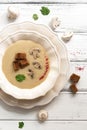 Cream of mushroom soup served in a white plate on a white wooden rustic table. Winter warming hot soup. Top view, flat lay Royalty Free Stock Photo