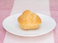 Cream puff on white dish, on pink tablecloth