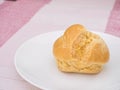 Cream puff on white dish, on pink tablecloth