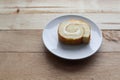 Cream roll cake sweet slice in white plate, delicious dessert isolated on wooden background closeup. Royalty Free Stock Photo