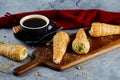 Cream Roll or cream buns served on wooden board with cup of black coffee on napkin side view of french breakfast baked