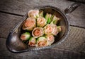 Cream roses in old metal bowl on wooden background