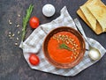 Cream soup of baked sweet pepper and tomato in a clay bowl on a brown concrete background. Served with dried white bread and Royalty Free Stock Photo