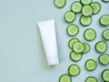 Cream tube and cucumber slices on light green background. White unbranded lotion, balsam, hand creme, toothpaste mockup. Clean
