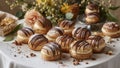 Creamfilled Pastries with Chocolate Drizzle on a White Table with Flowers in Background. Royalty Free Stock Photo