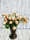Creamy bouquet of roses in a vase on a wooden background