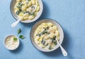 Creamy cheesy spinach potato gnocchi on a blue background, top view. Mediterranean food