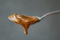 Creamy chocolate hazelnut spread dripping from a spoon, against a grey background Royalty Free Stock Photo