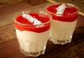 Creamy dessert with strawberry sauce and coconut flakes in glasses Royalty Free Stock Photo