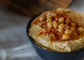 Creamy hummus with chickpeas and red spices in dark bowl in light kitchen. Close-up Royalty Free Stock Photo