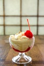 Creamy ice cream with cherries on plate in glass bowl, on wooden Royalty Free Stock Photo