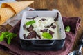 Creamy mint ice cream with chocolate chips in a black ceramic mold on a brown wooden background. Ice cream recipes